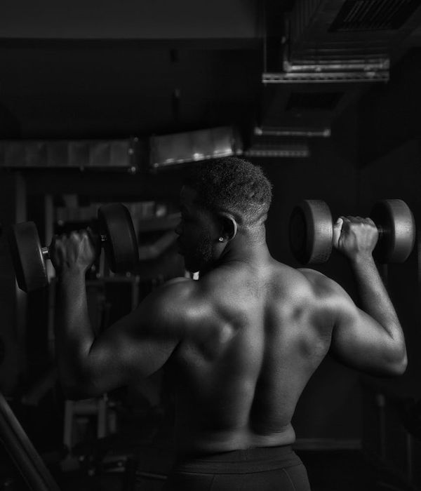Muscular man performing steady power exercises in a dark gym